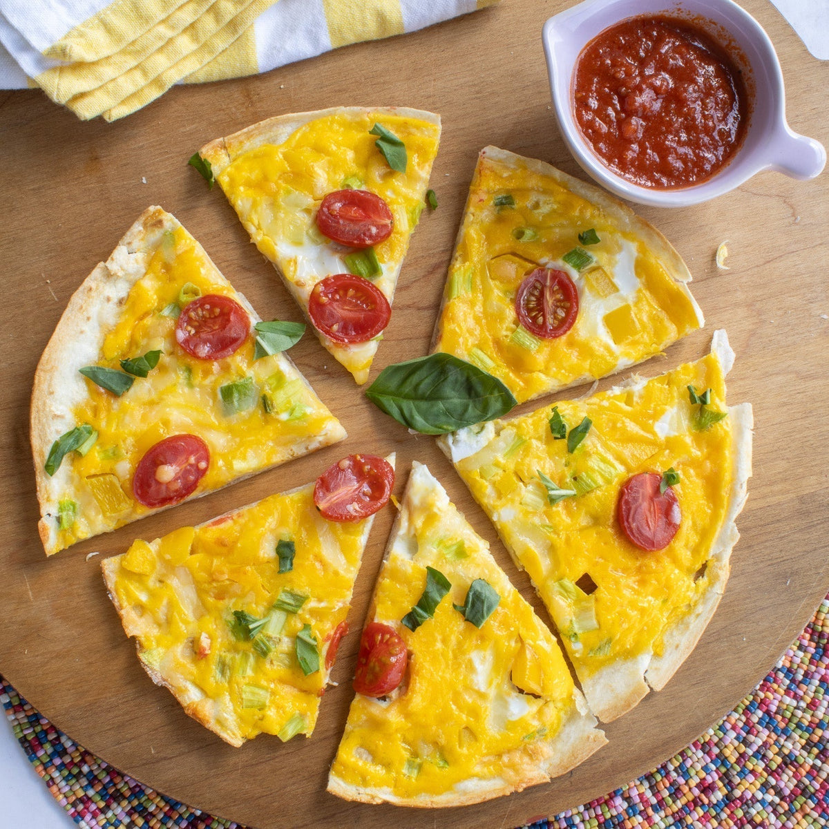 Easy Breakfast Pizza on a cutting board with a side of marinara sauce. 