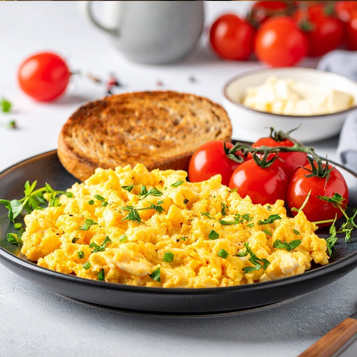 A plate of scrambled Nellie's Free Range eggs with tomatoes, and toast.