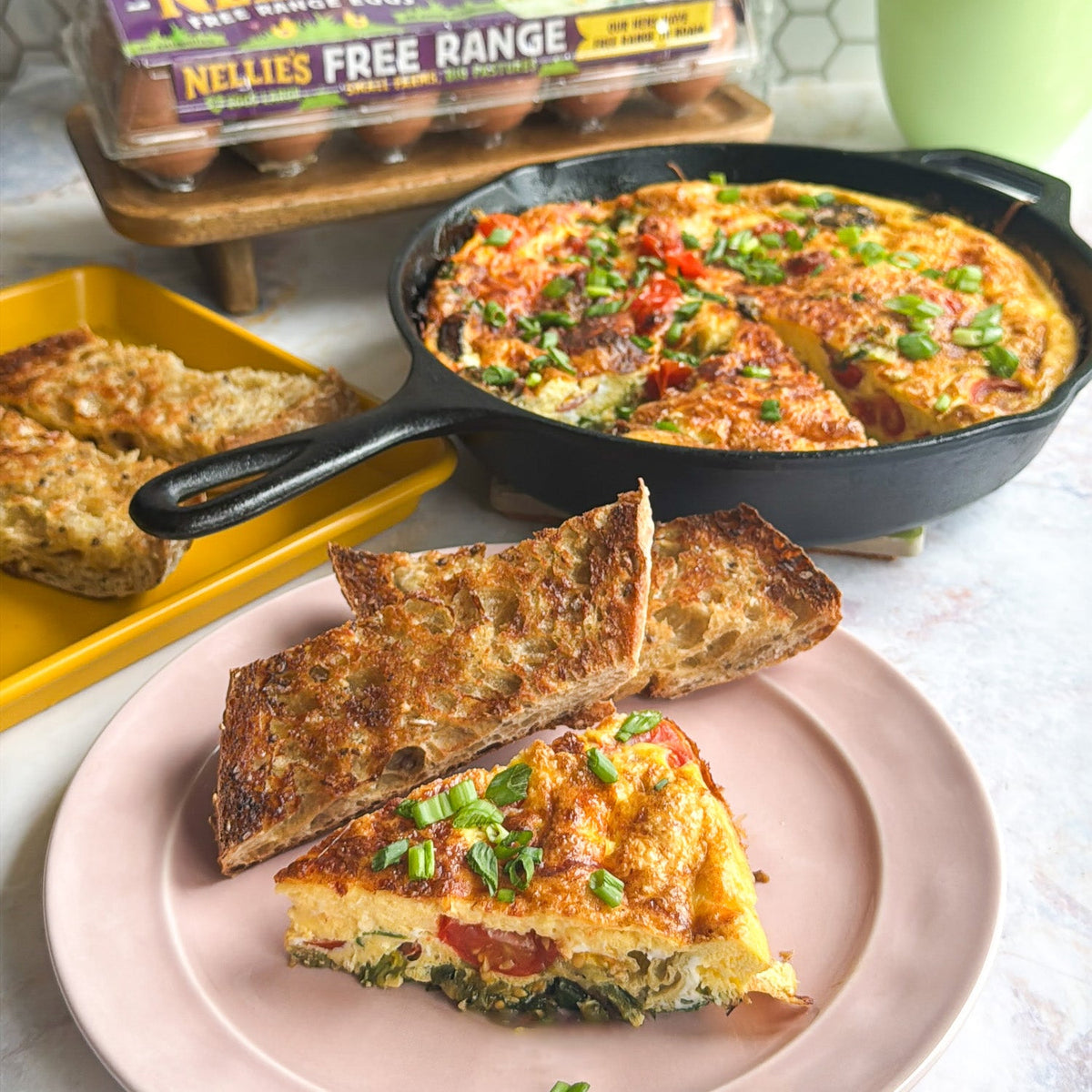 Veggie Frittata on a place with toast next to a skillet full of frittata.